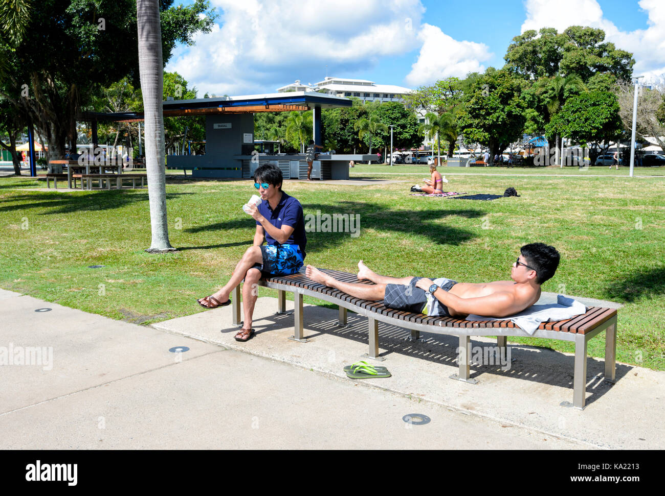 Junge Asiatische Männer Entspannen und Sonnenbaden auf der Esplanade, Cairns, Far North Queensland, FNQ, QLD, Australien Stockfoto