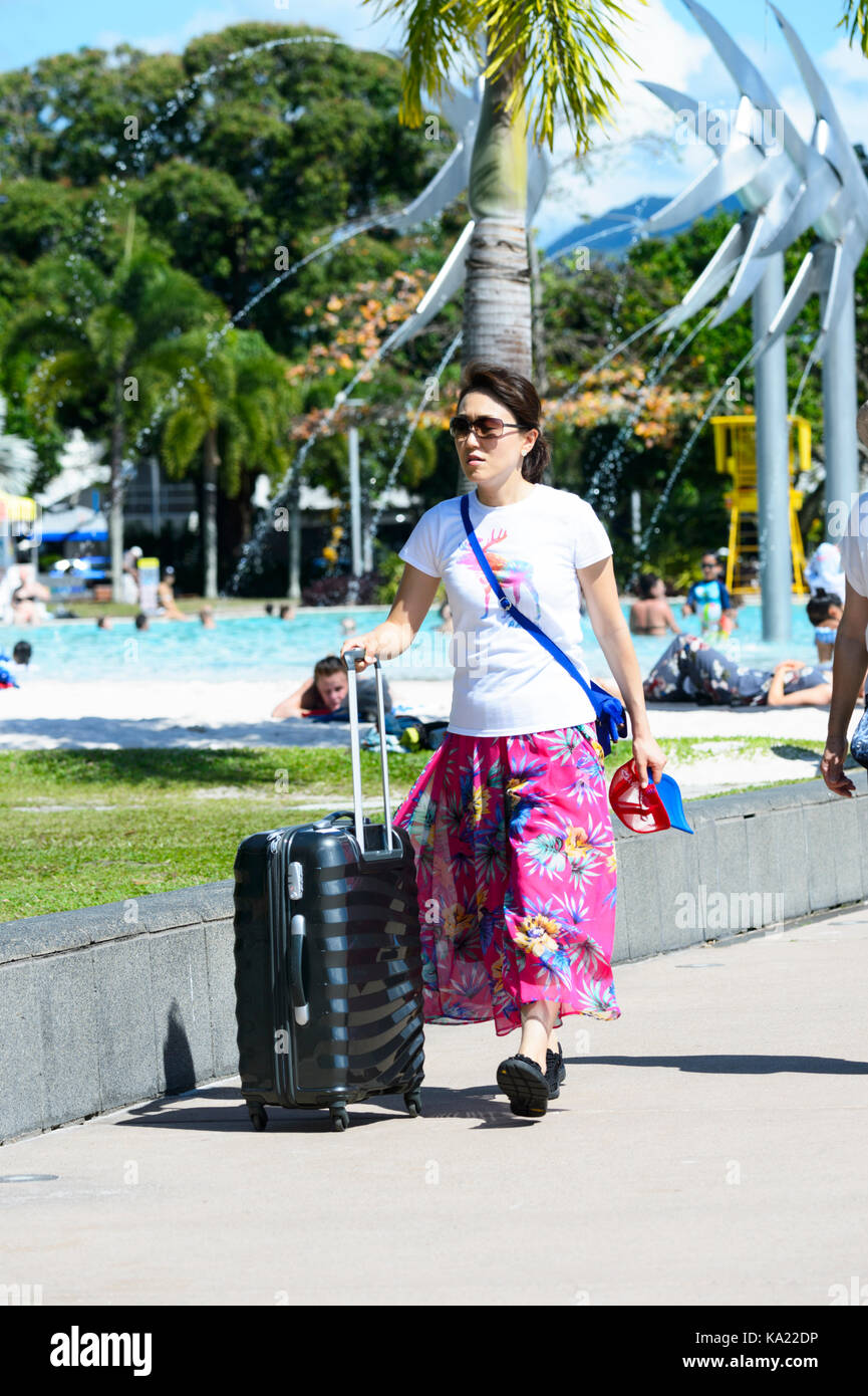 Junge asiatische Frau entlang der Esplanade mit einem Koffer, Cairns, Far North Queensland, FNQ, QLD, Australien Stockfoto