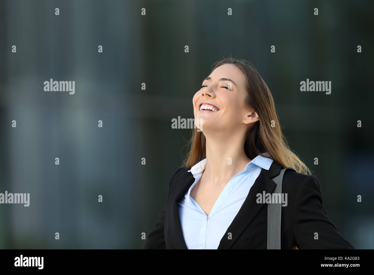 Single glücklich erfolgreiche Führungskraft atmet tief die frische Luft auf der Straße mit einem Bürogebäude im Hintergrund Stockfoto