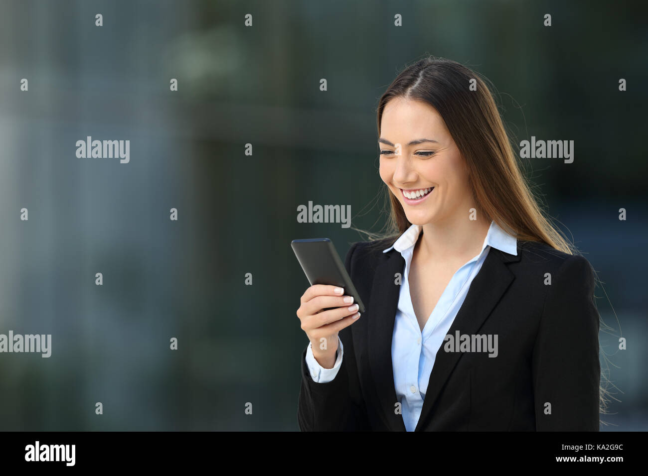Single smiley executive Frau über ein Mobiltelefon mit einem Fuß auf der Straße Stockfoto