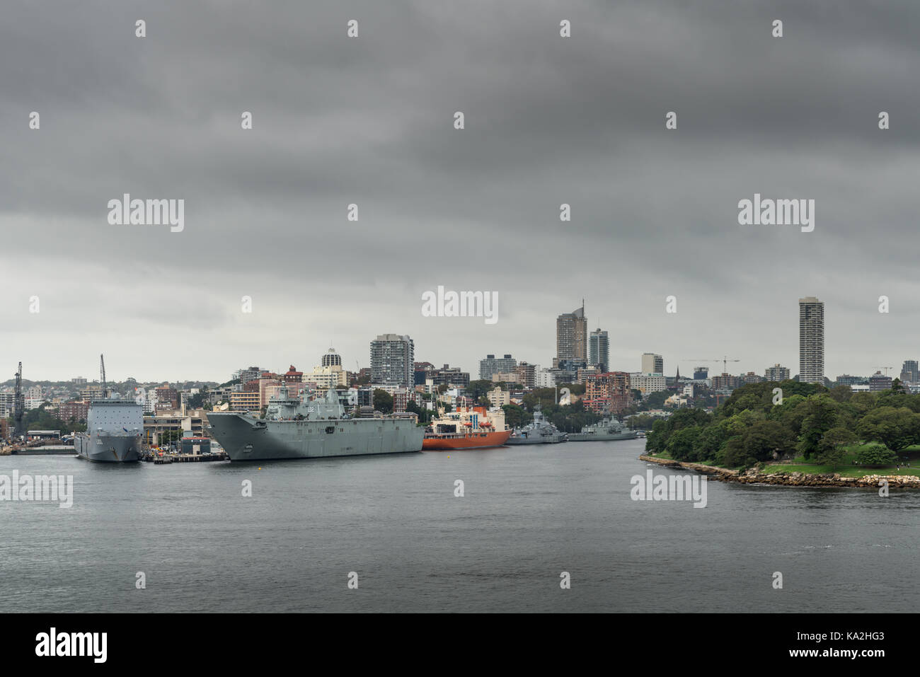 Sydney, Australien - 21. März 2017: Mehrere Marine Schiffe angedockt entlang der Garden Island Kais unter regnerisch, stürmisch cloudscape und die Skyline der Stadt. Teil von Frau Stockfoto