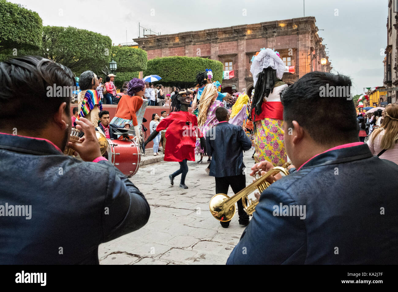Eine marching band folgt eine Parade der Riesen papier - mache Marionetten namens mojigangas in einer Prozession durch die Stadt zu Beginn des einwöchigen Fiesta des Schutzheiligen St. Michael 22. September 2017 in San Miguel de Allende, Mexiko. Stockfoto