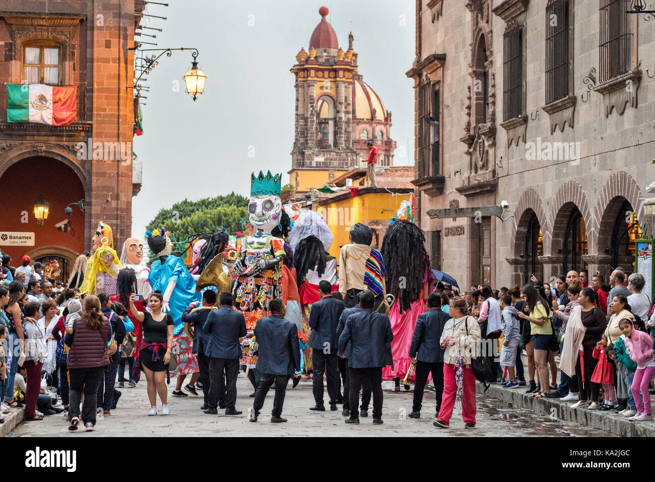 Eine marching band folgt eine Parade der Riesen papier - mache Marionetten namens mojigangas in einer Prozession durch die Stadt zu Beginn des einwöchigen Fiesta des Schutzheiligen St. Michael 22. September 2017 in San Miguel de Allende, Mexiko. Stockfoto