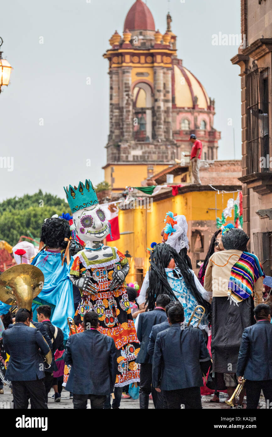 Eine marching band folgt eine Parade der Riesen papier - mache Marionetten namens mojigangas in einer Prozession durch die Stadt zu Beginn des einwöchigen Fiesta des Schutzheiligen St. Michael 22. September 2017 in San Miguel de Allende, Mexiko. Stockfoto