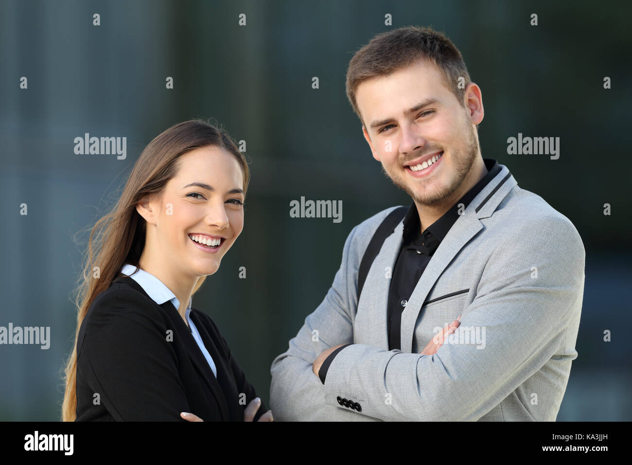 Paar Führungskräfte posiert an der Kamera stehen auf der Straße mit einem Büro Gebäude im Hintergrund Stockfoto