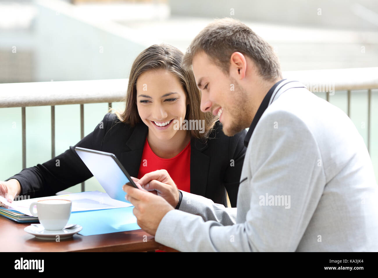 Zwei Führungskräfte Beratung online Daten in einer Tablette in einem Restaurant Terrasse sitzen Stockfoto