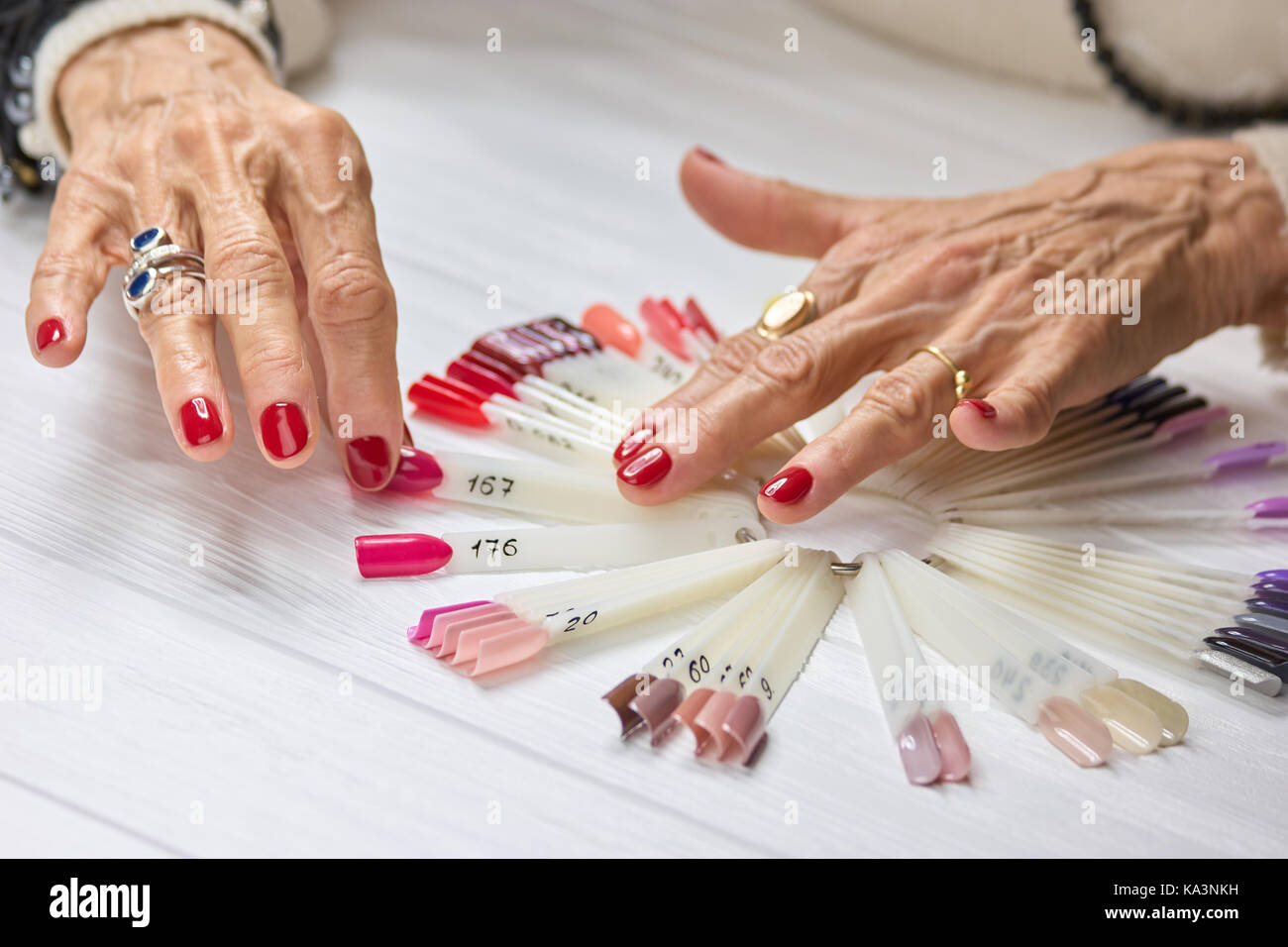 Senior womans Hände mit roten Maniküre. Schöne alte Frau Hände mit perfekter Rote nägel Auswahl Sommer rosa Nagel Sample. Stockfoto