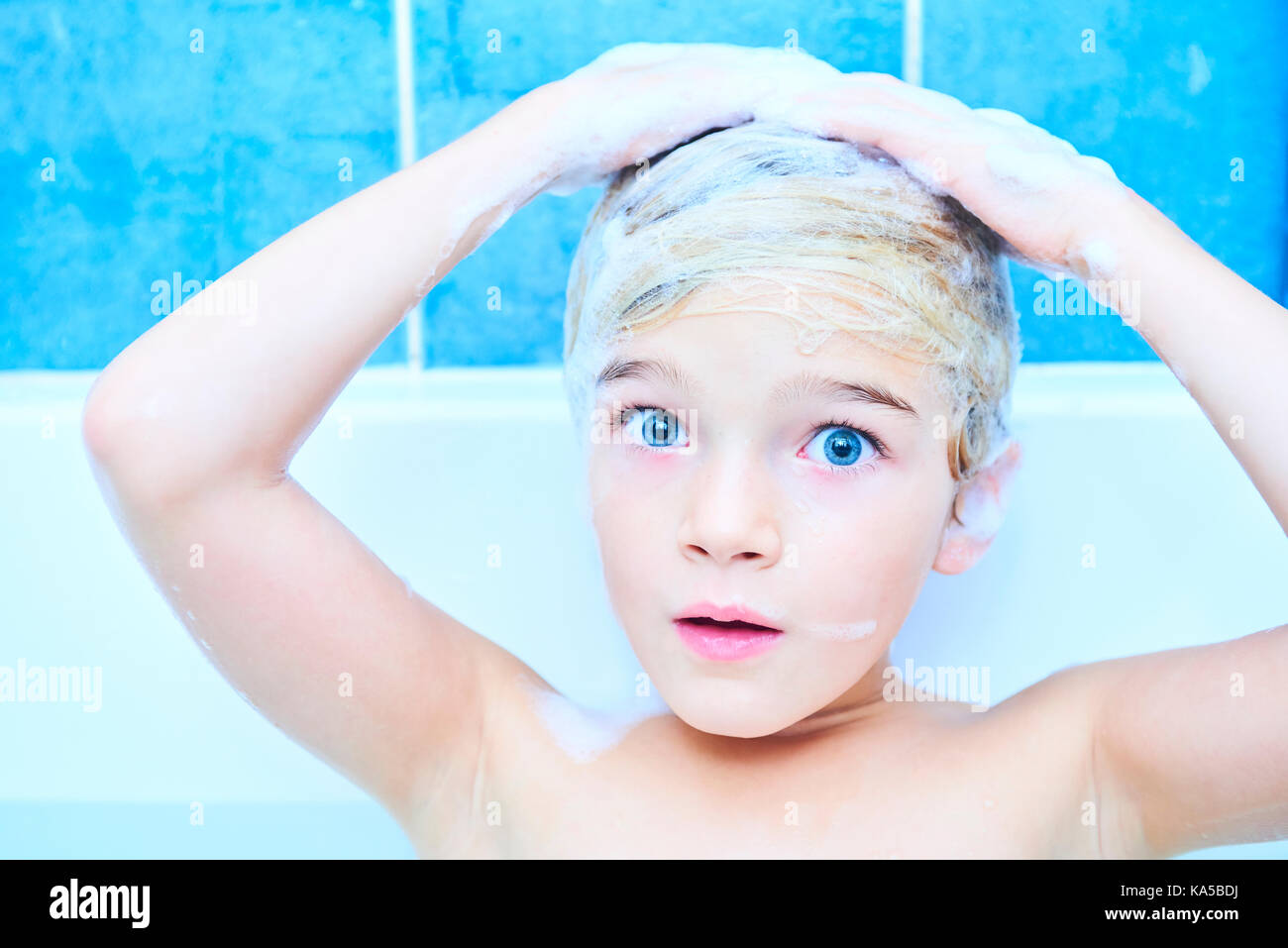 Kind, Mädchen mit nassen langen Haar nimmt ein Schaumbad. Waschen ihre Haare mit Shampoo und Spaß haben Stockfoto