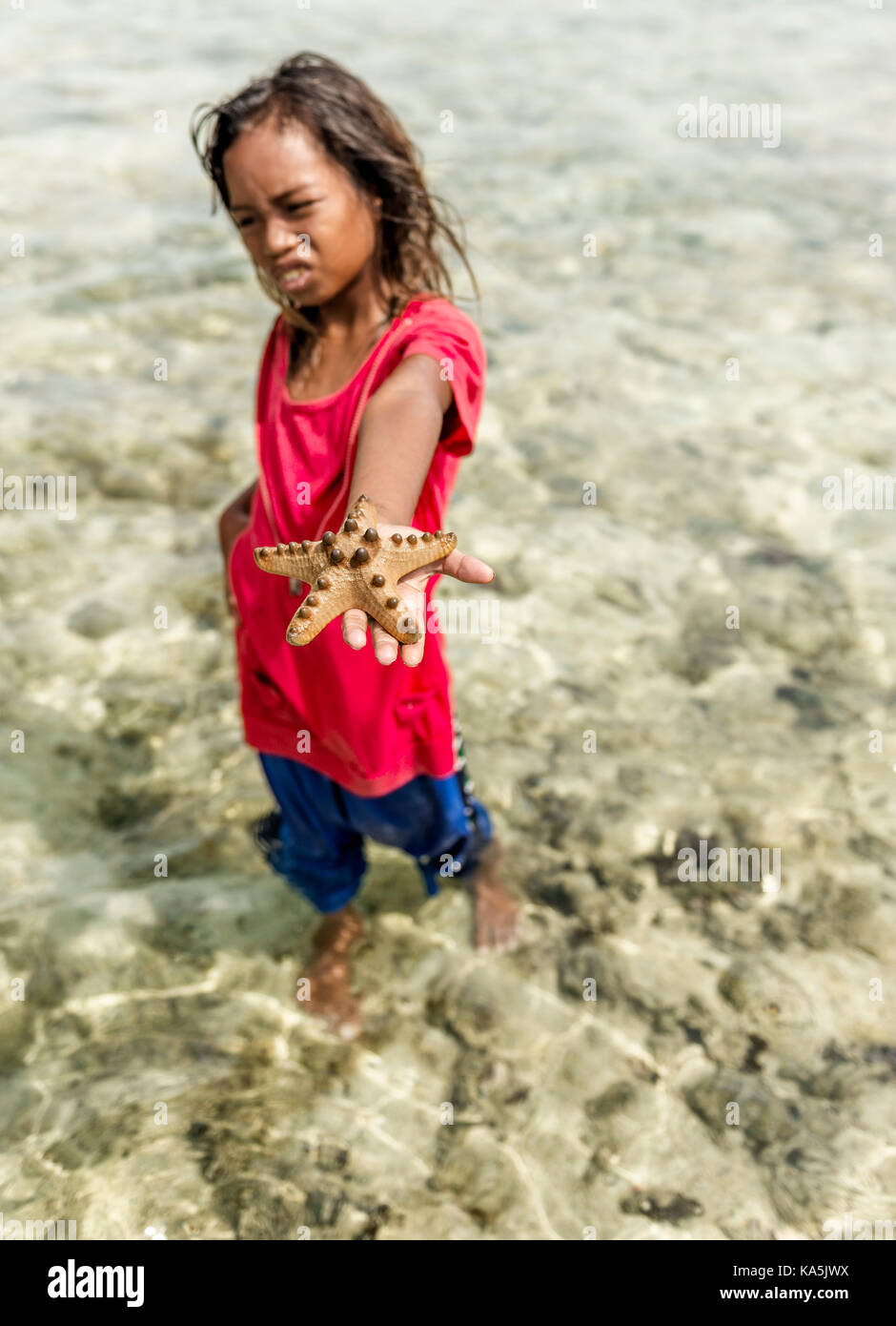 Kleine Mädchen spielen mit Seestern in Semporna Meer Stockfoto