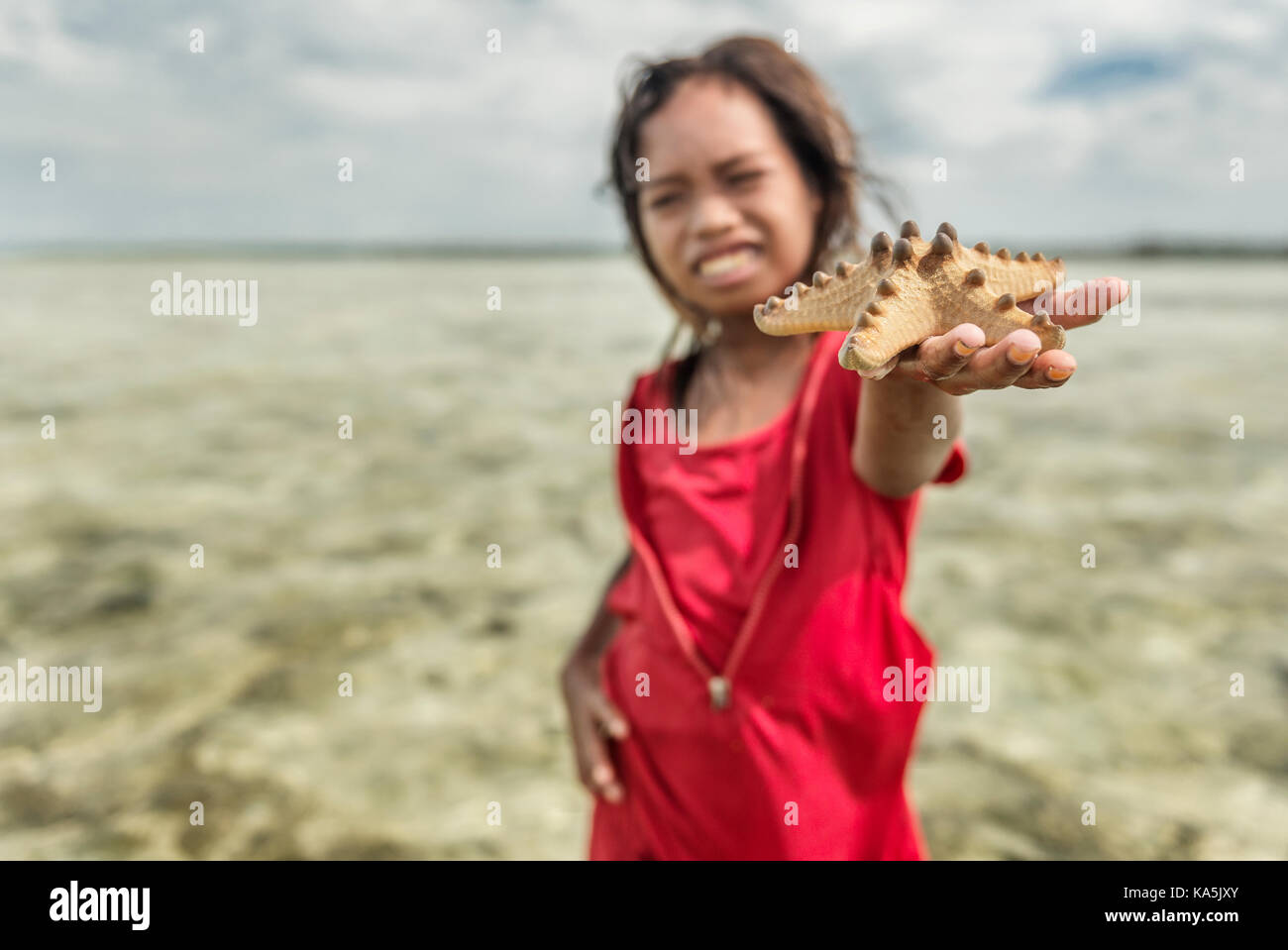 Kleine Mädchen spielen mit Seestern in Semporna Meer Stockfoto