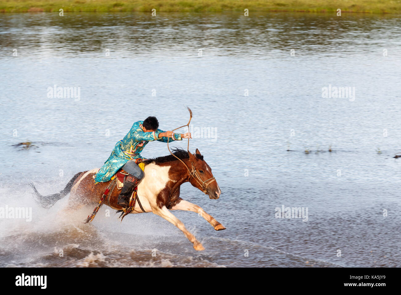 Junge mongolische Reiter reitet in vollem Galopp auf dem Fluss Stockfoto
