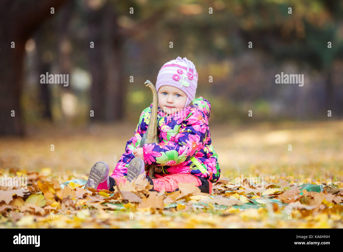 Kleine Mädchen spielen mit Spielzeug Dinosaurier im Herbst Park Stockfoto