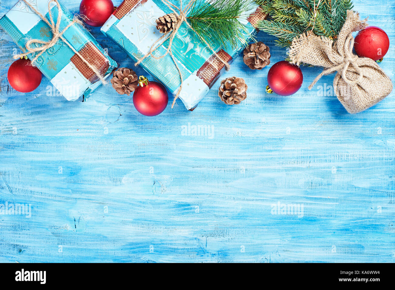 Blick von oben auf die Weihnachten Hintergrund auf Blau Holzbrett mit Tanne, rot Dekorationen, Kegel und Geschenkboxen bilden oben Rim. kopieren. Stockfoto