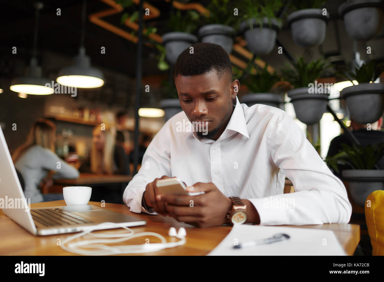 Ernsthafte afrikanischer Mann chatten, schreiben Nachricht smart phone. Stockfoto