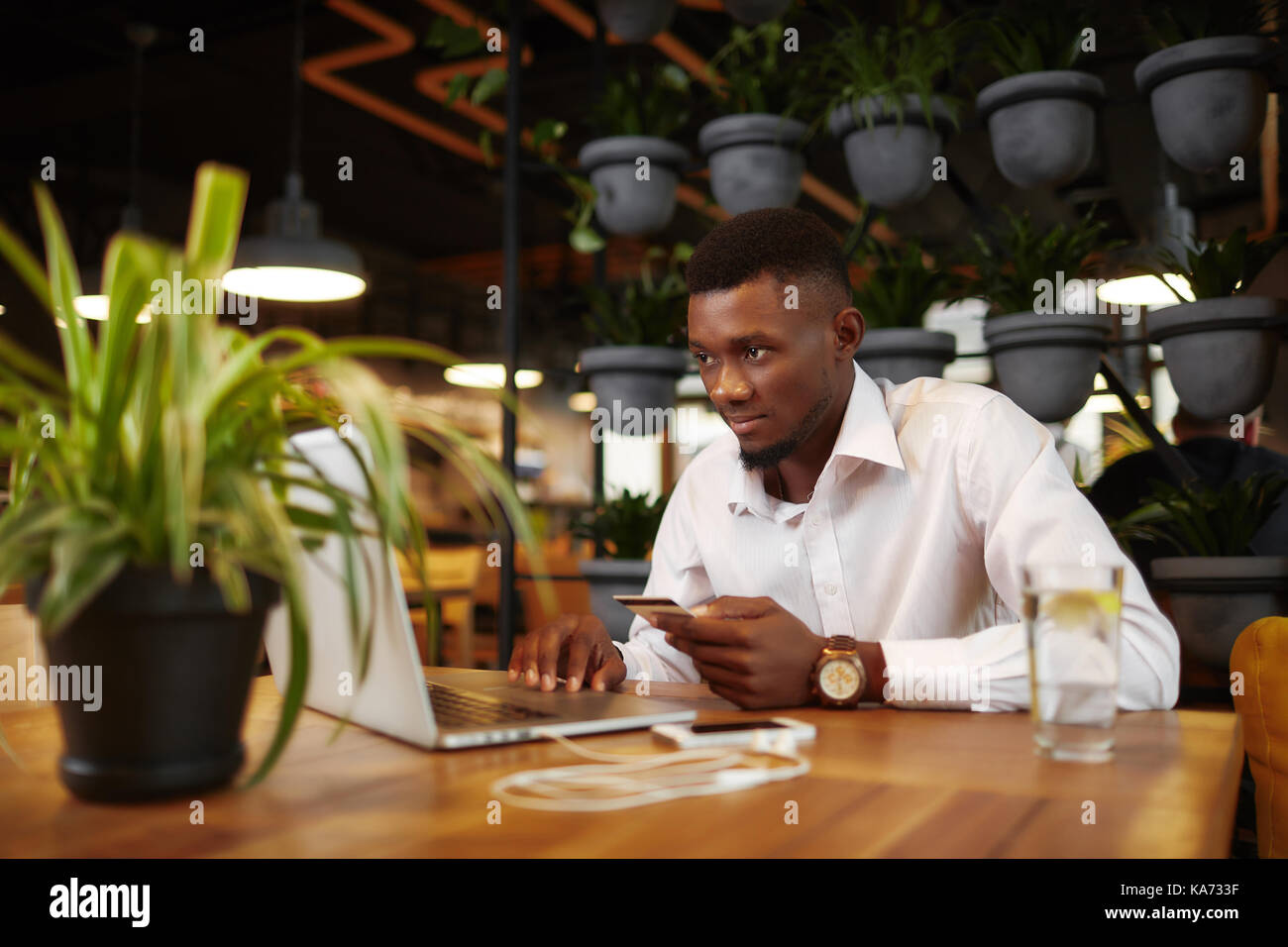 Afrikanischer Mann im Internet Shop mit Karte und Laptop shoping. Stockfoto