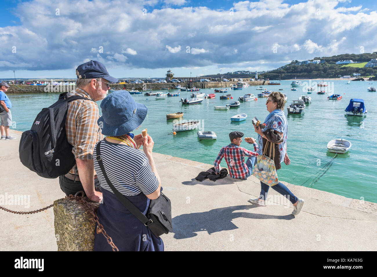 St Ives - Urlauber entspannen und genießen den Blick über den Hafen von St Ives in Cornwall. Stockfoto