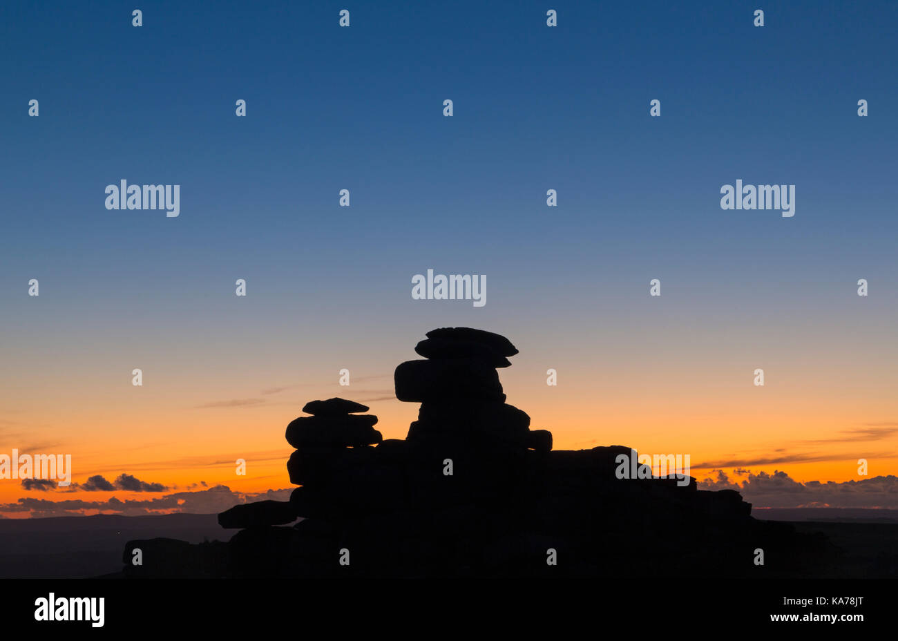 Sonnenuntergang Die Sonne taucht hinter dem Granit Felsen silhouetting ihre Formen an der Großen Heften Tor, Nationalpark Dartmoor, Devon, UK im September Stockfoto