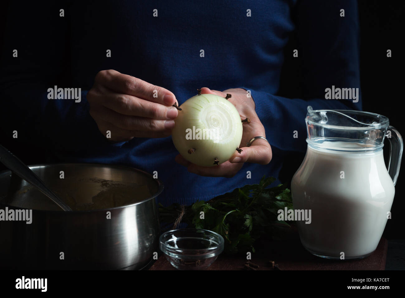 Große Zwiebel in Händen, Kanne mit Milch auf einem blauen Hintergrund horizontal Stockfoto