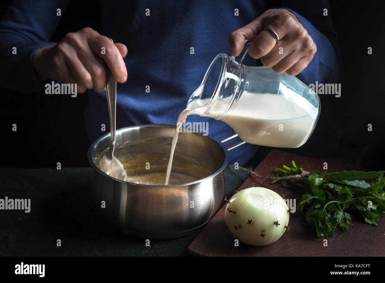 Milch aus der Kanne ist in eine Basis-Sauce für die béchamelsoße Horizontale gegossen Stockfoto