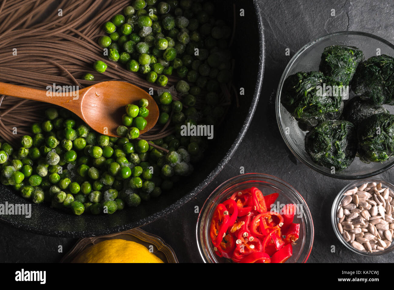 Buchweizen Nudeln in einer Pfanne und gefrorene Erbsen, Chili und Samen in eine Schüssel horizontal Stockfoto
