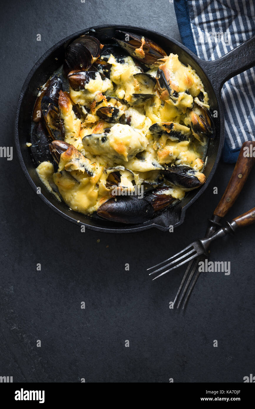 Miesmuscheln mit Käse Sauce in einer Pfanne, Serviette und Gabeln freien Speicherplatz, vertikal Stockfoto