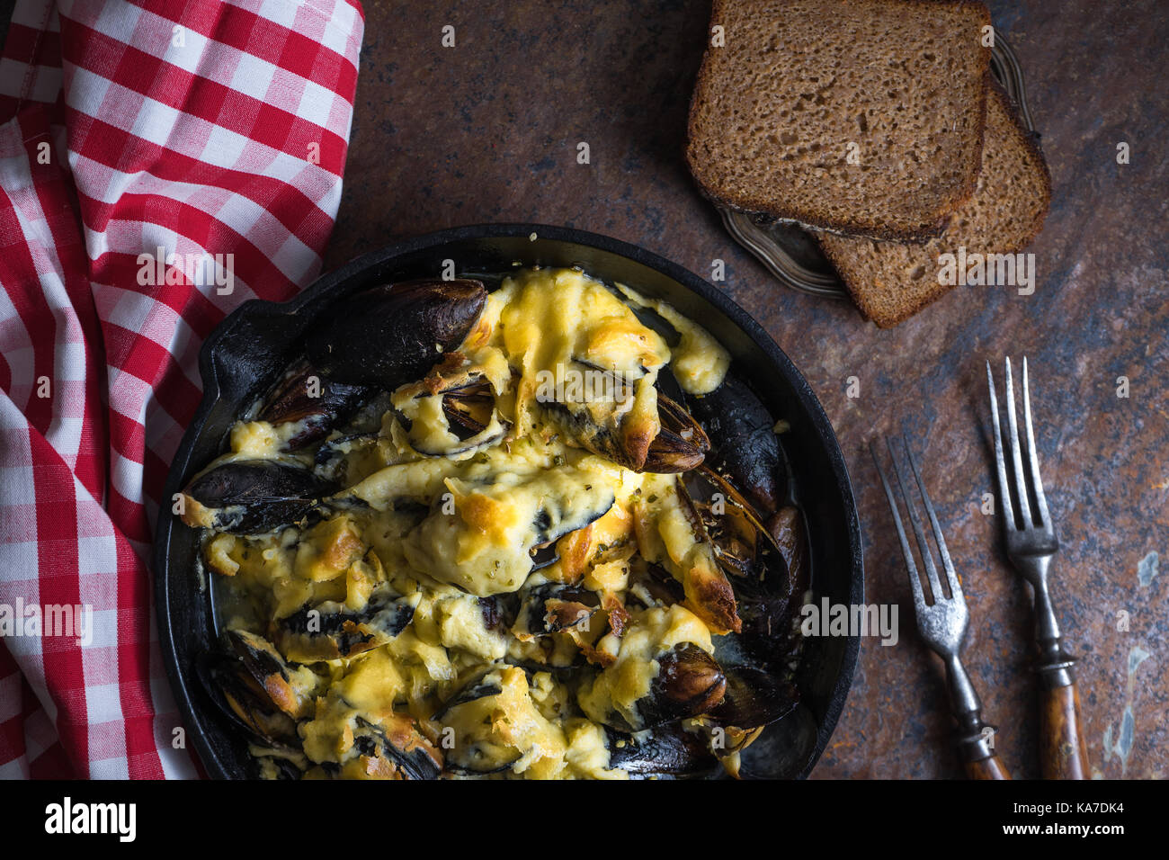 Miesmuscheln mit Käse Sauce in einer Pfanne, Serviette in einem roten Käfig close-up horizontal Stockfoto