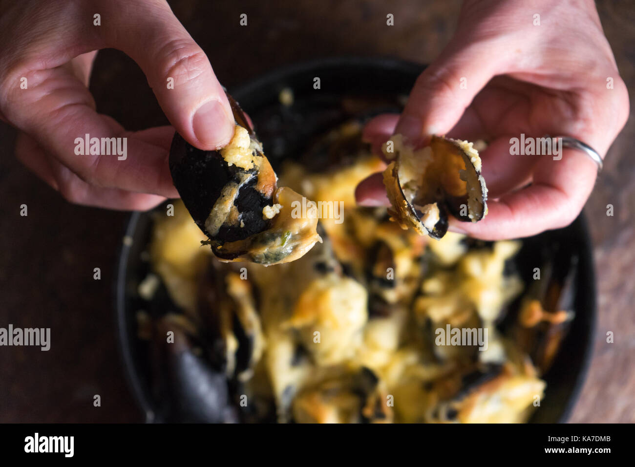 Weibliche Hände öffnen die Türen von Muscheln mit Käsesoße horizontal Stockfoto