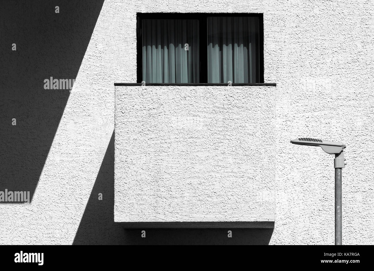 Abstrakte moderne, minimalistische Architektur mit Balkon, Fenster und Straßenlaterne. Hoher Kontrast outdoor Fassade Bild Stockfoto