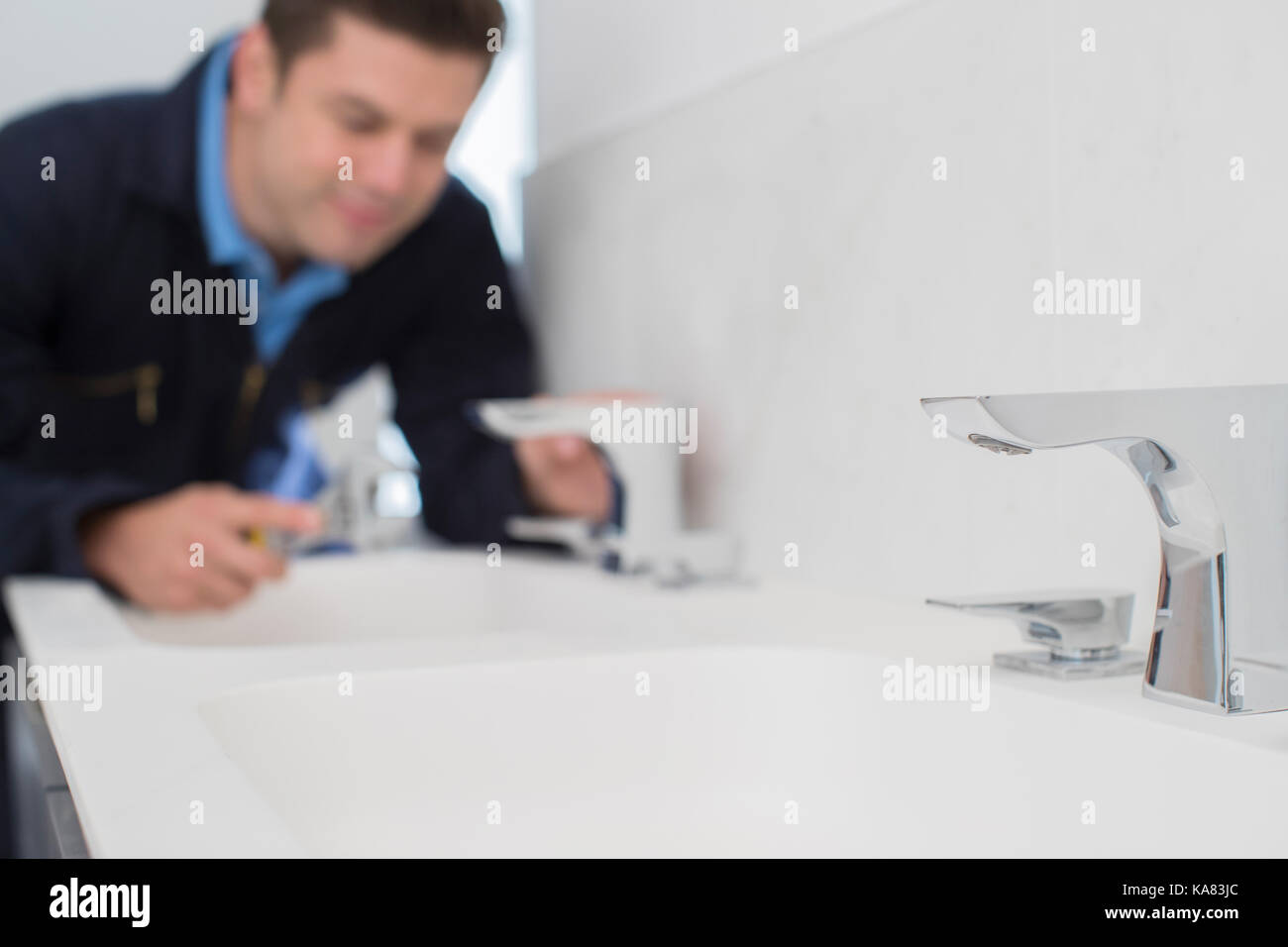 Klempner Arbeiten am Waschbecken im Badezimmer mit einem Schraubenschlüssel Stockfoto