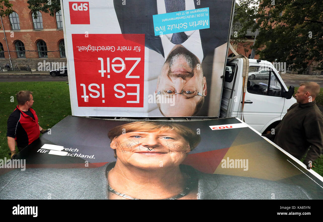 Berlin, Deutschland. 25 Sep, 2017. Die Arbeitnehmer tragen ein CDU-Plakat zeigt, dass Bundeskanzlerin Merkel und von einem SPD-Plakat mit Schulz's Gesicht in Berlin, Deutschland, 25. September 2017. Quelle: Wolfgang Kumm/dpa/Alamy leben Nachrichten Stockfoto