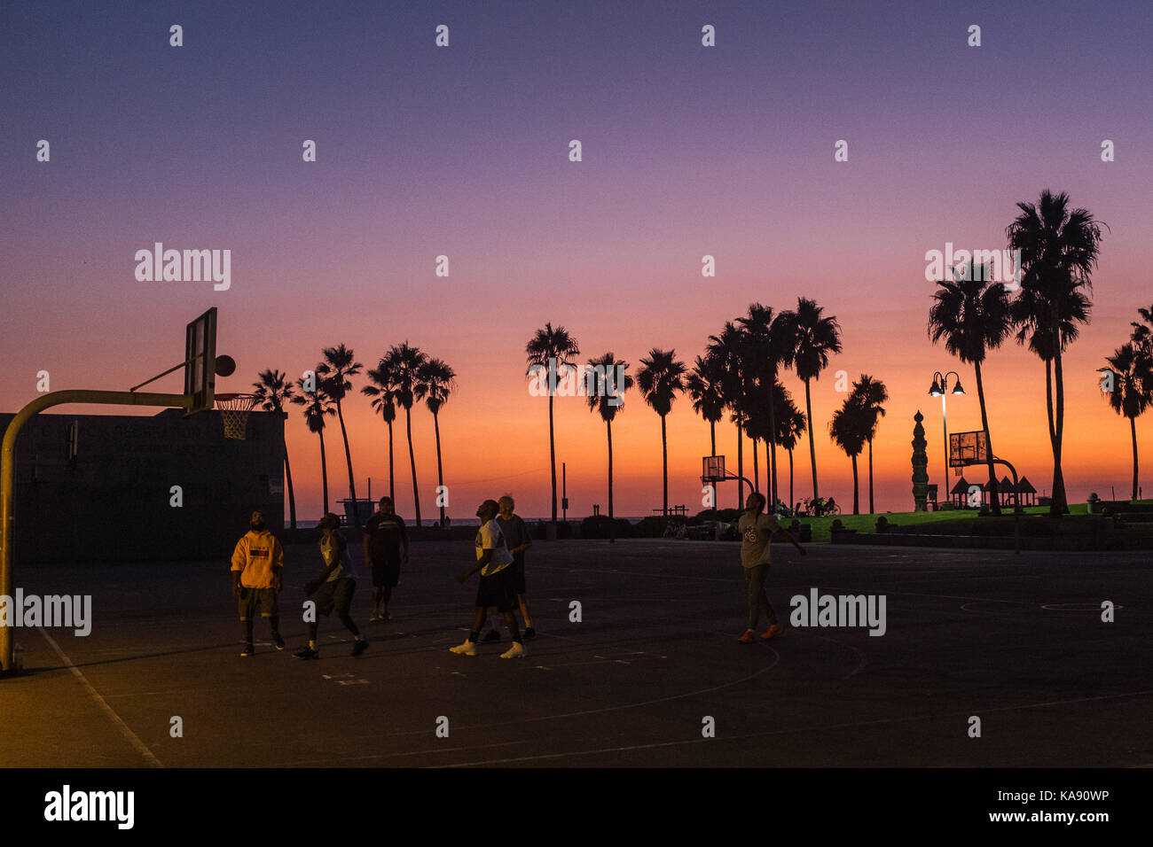 Menschen spielen Basketball während Sonnenuntergang am Venice Beach, Los Angeles, mit Blick auf den Pazifischen Ozean Stockfoto
