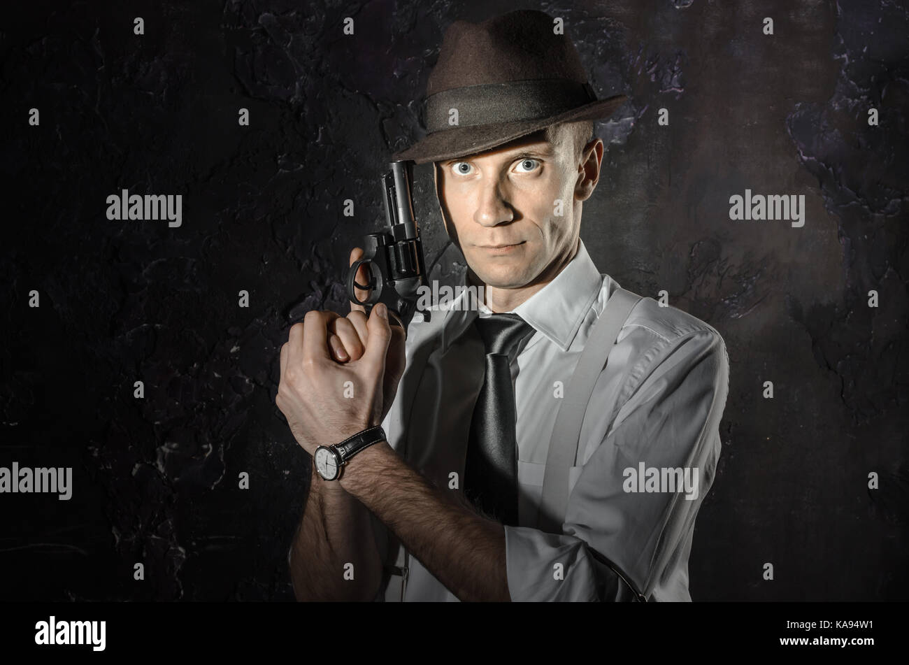 Schwarz-weiß Bild von einem Privatdetektiv mit einer Pistole in beiden Händen. Agent in stylischen Hut. Man bleibt vor der Kamera. Er trägt Classic Shirt mit Stockfoto