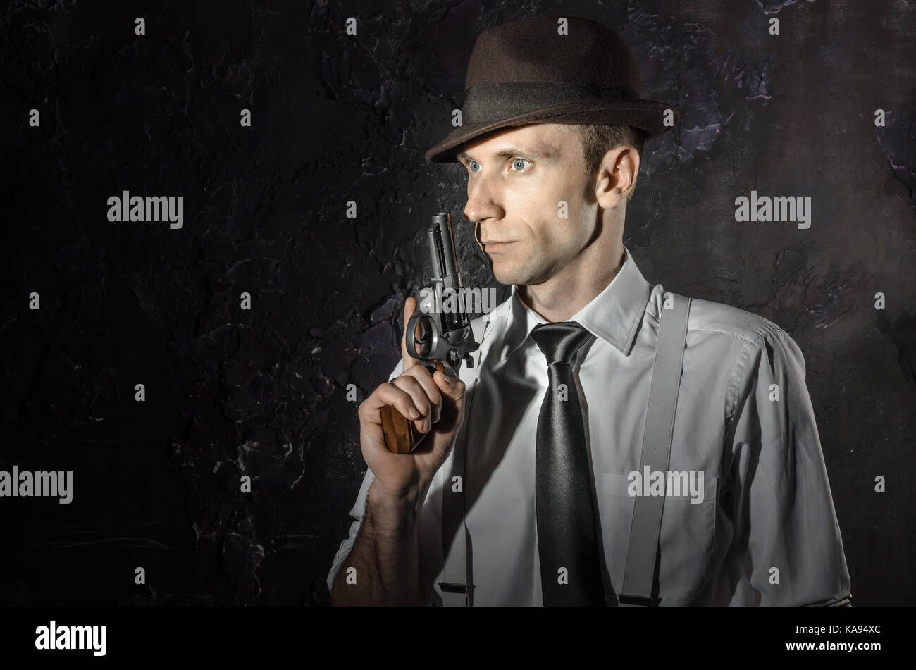 Schwarz-weiß Bild von einem Privatdetektiv mit einer Pistole in beiden Händen. Agent in stylischen Hut. Man bleibt vor der Kamera. Er trägt Classic Shirt mit Stockfoto
