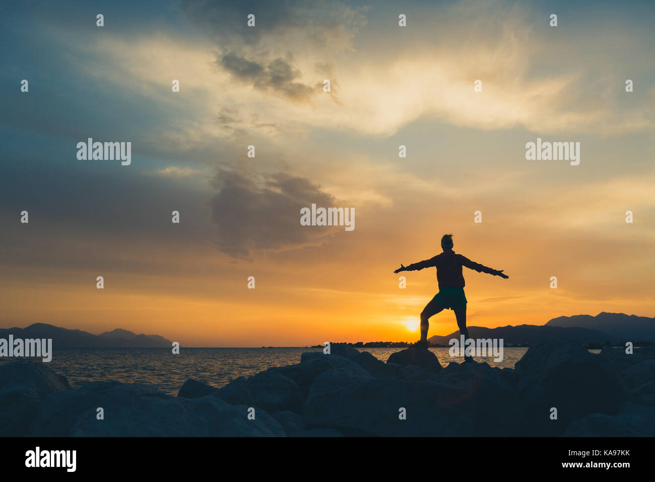 Frau mit ausgestreckten Armen an einem Meer. Schöne inspirierende Landschaft und Meer mit Mädchen und die Hände auf den Sonnenuntergang, Kroatien. Stockfoto