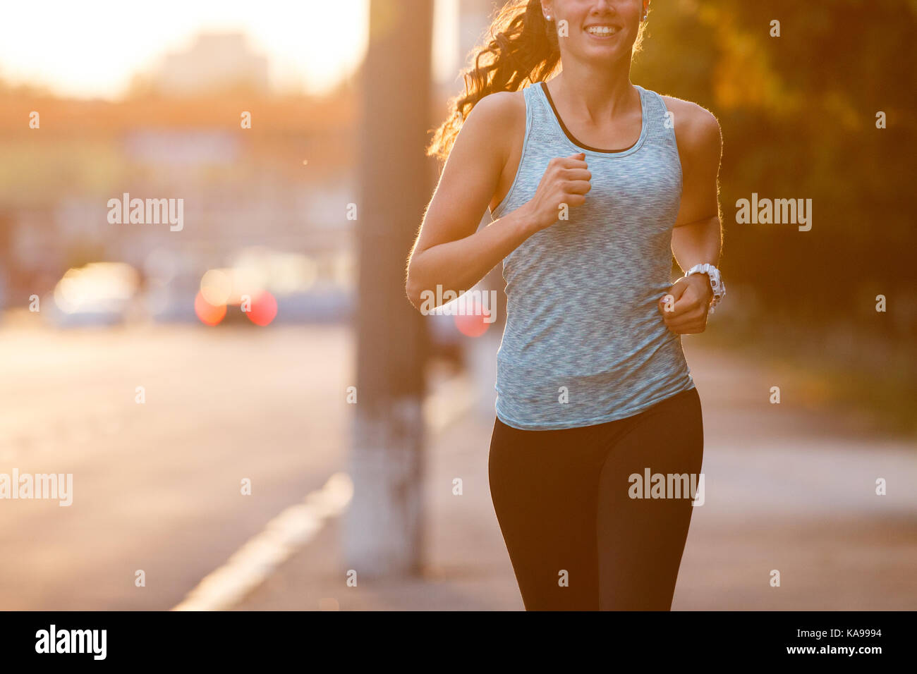 Junge lächelnde sportliche Frau, die auf Pflaster am Morgen. Fitness Mädchen Joggen im Park Stockfoto
