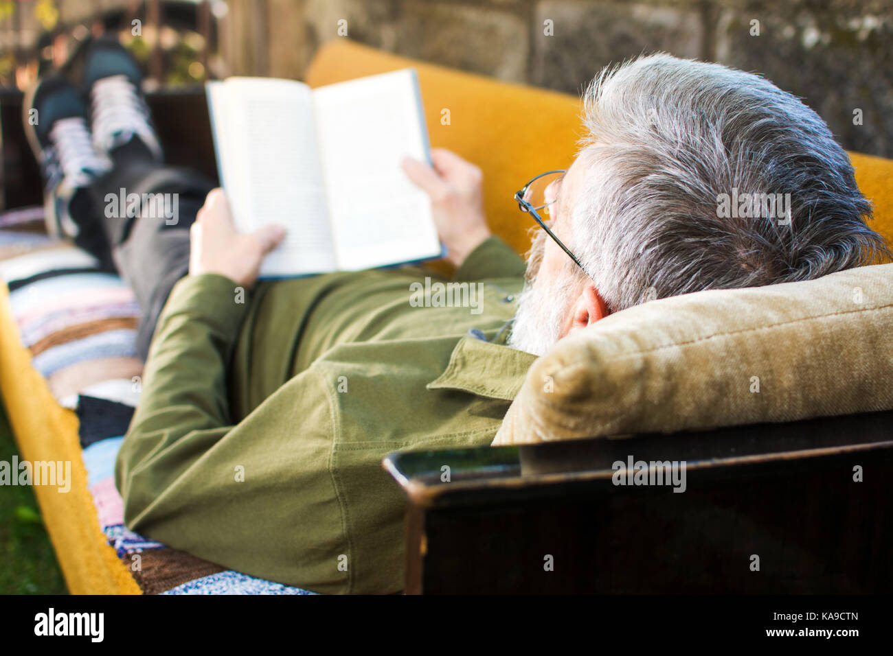 Ältere Menschen mit einem Buch auf einem Bett im Hinterhof Stockfoto