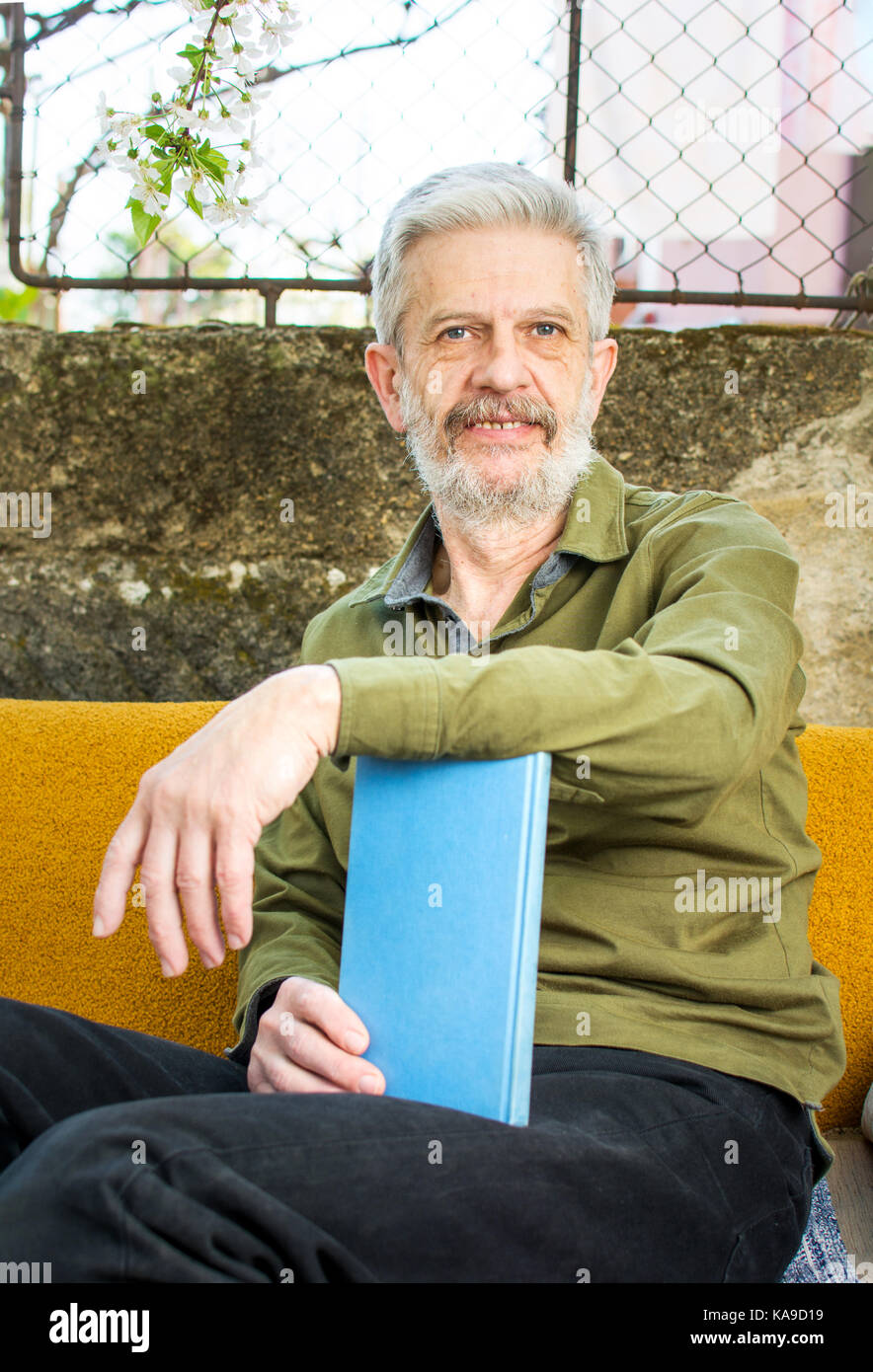 Ältere Menschen mit einem Buch in den Hinterhof sitzen Stockfoto