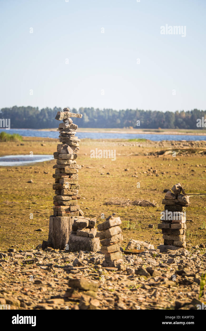 Sonnige Auenlandschaft eines ausgetrockneten Flussbett und Felsen. Stein balancing Konstruktionen in der Nähe des Flusses. Felsige Flusslandschaft. Stockfoto