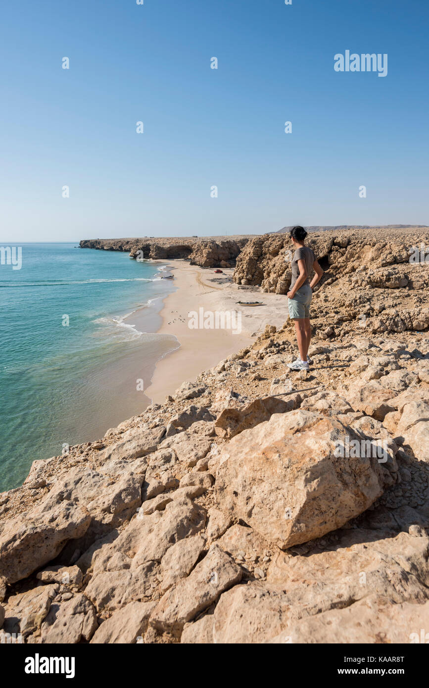 Frau, die den wilden Strand, die Küste von Ras Al Jinz, das Sultanat von Oman bewundert, vertikale Aussicht perfekt für Reisekonzepte und Reiseziele Stockfoto