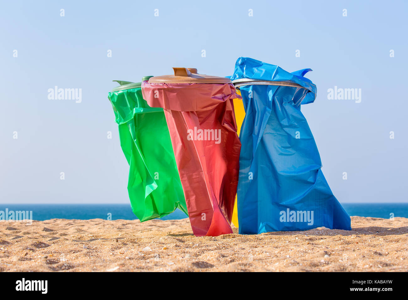 Bunte Müllsäcke am Strand mit Blick aufs Meer Stockfoto