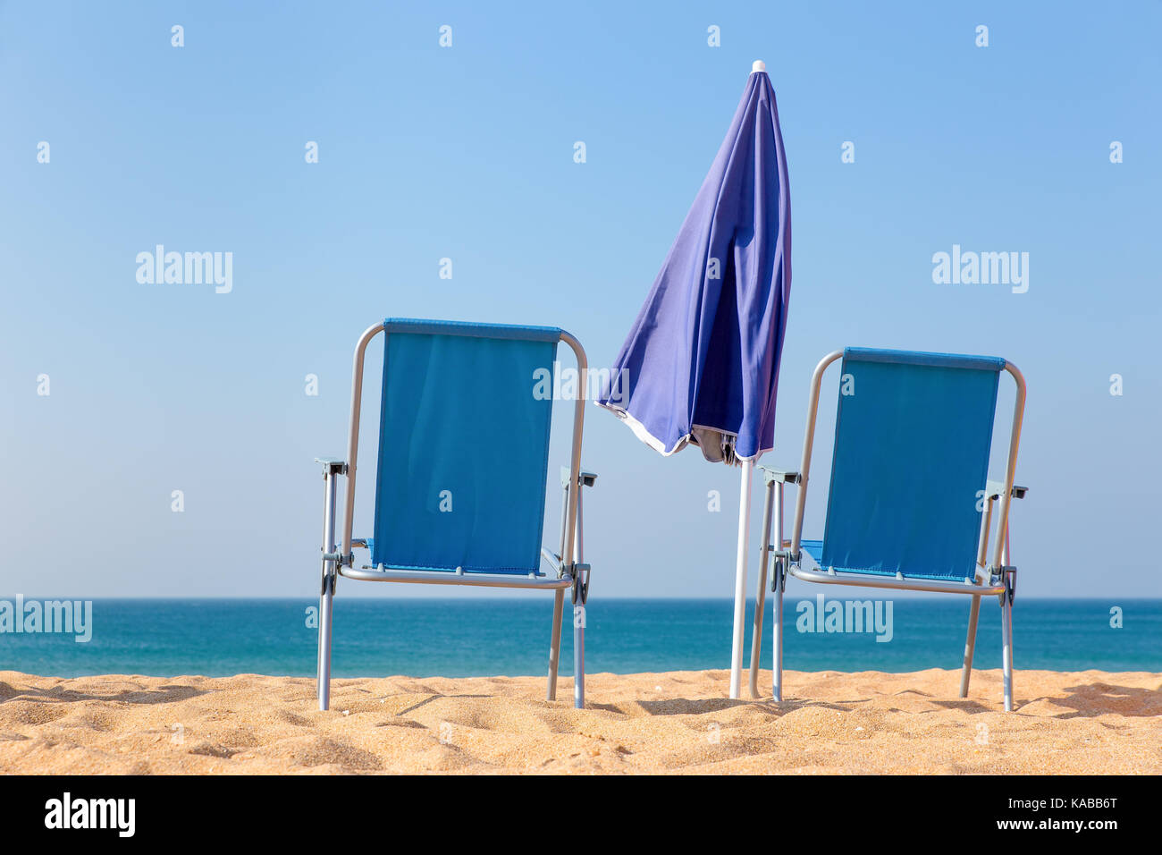 Zwei leere blaue Liegestühle und Sonnenschirm am Meer Stockfoto