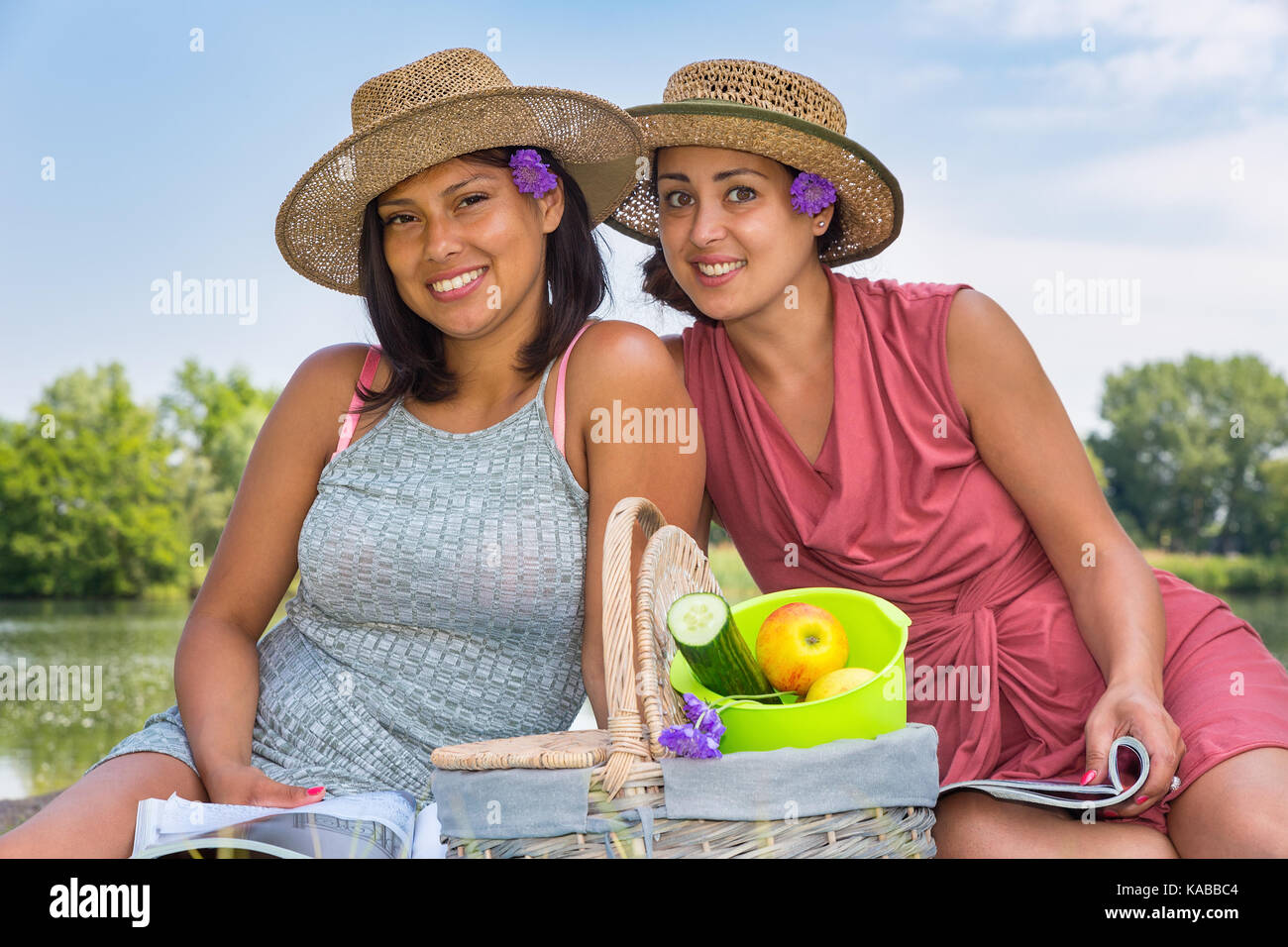Zwei Freunde mit Hüten und Picknickkorb an Wasser in der Natur Stockfoto