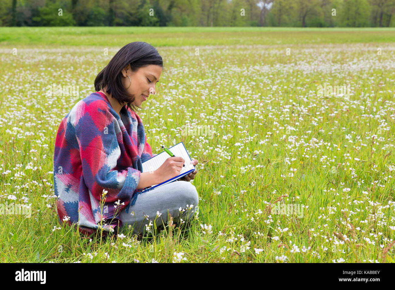 Kolumbianische Frau sitzt im niederländischen Wiese mit Blumen Stockfoto