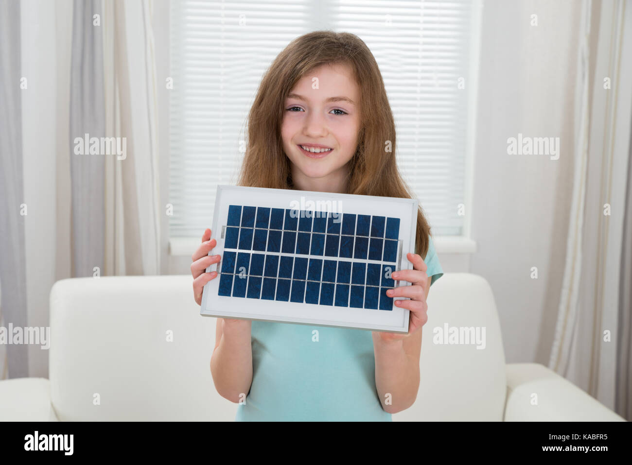 Happy girl Holding Solar Panel im Wohnzimmer Stockfoto