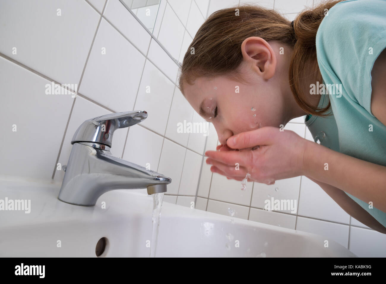 Kleines Mädchen Waschen mit Wasser im Badezimmer Stockfoto