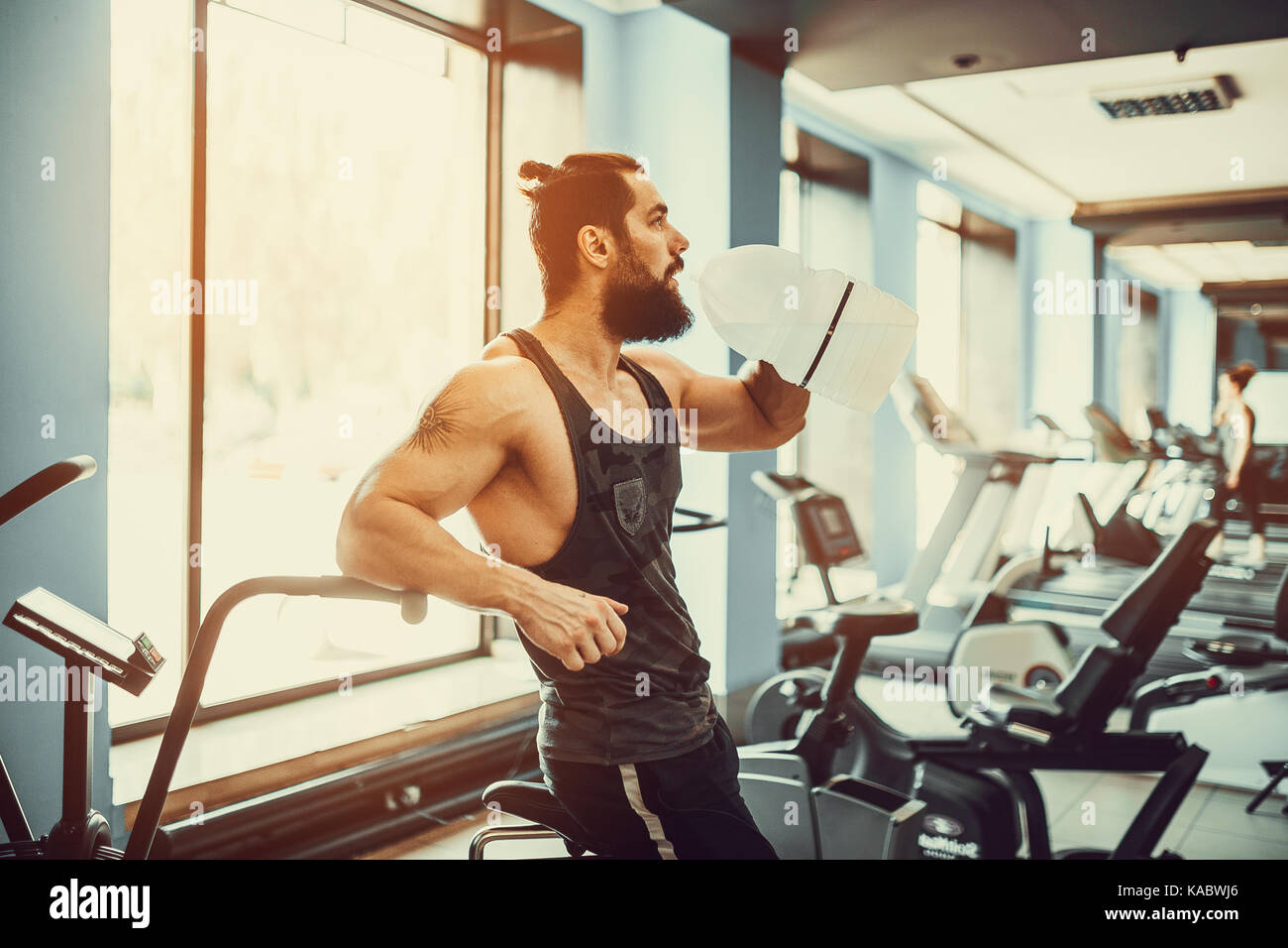 Guy Entspannung nach Training und Halten oder Trinke Wasser aus großen Flasche in der Turnhalle Stockfoto