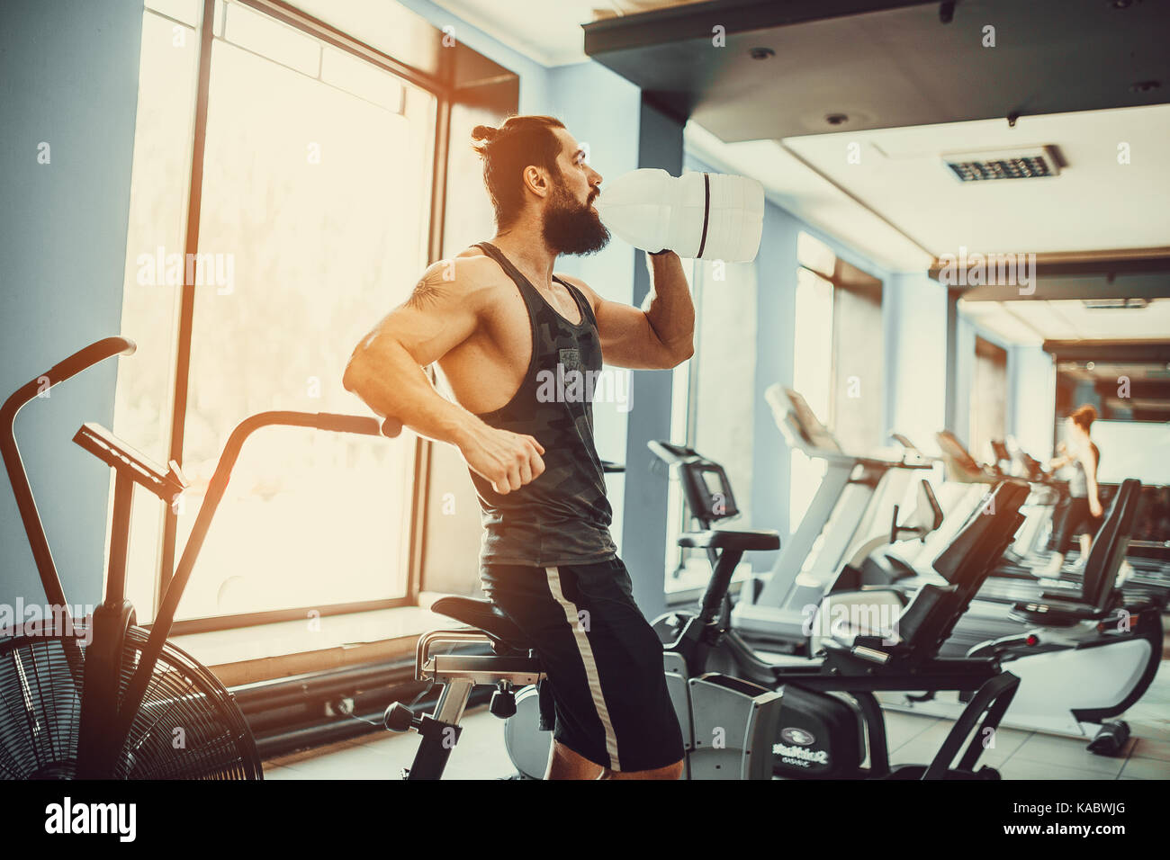 Guy Entspannung nach Training und Halten oder Trinke Wasser aus großen Flasche in der Turnhalle Stockfoto
