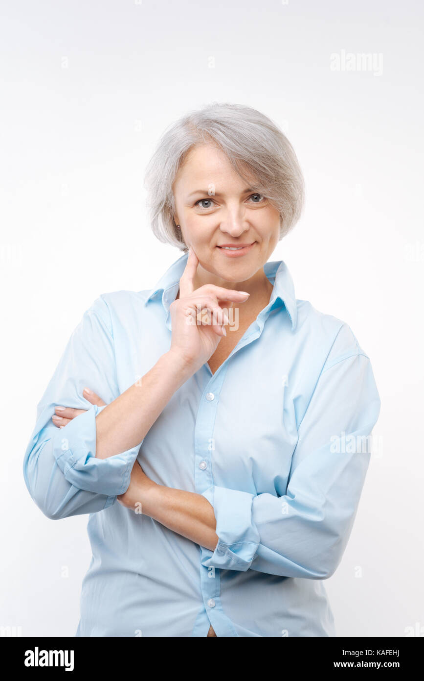 Grauhaarige Frau Wange mit dem Finger berühren Stockfoto