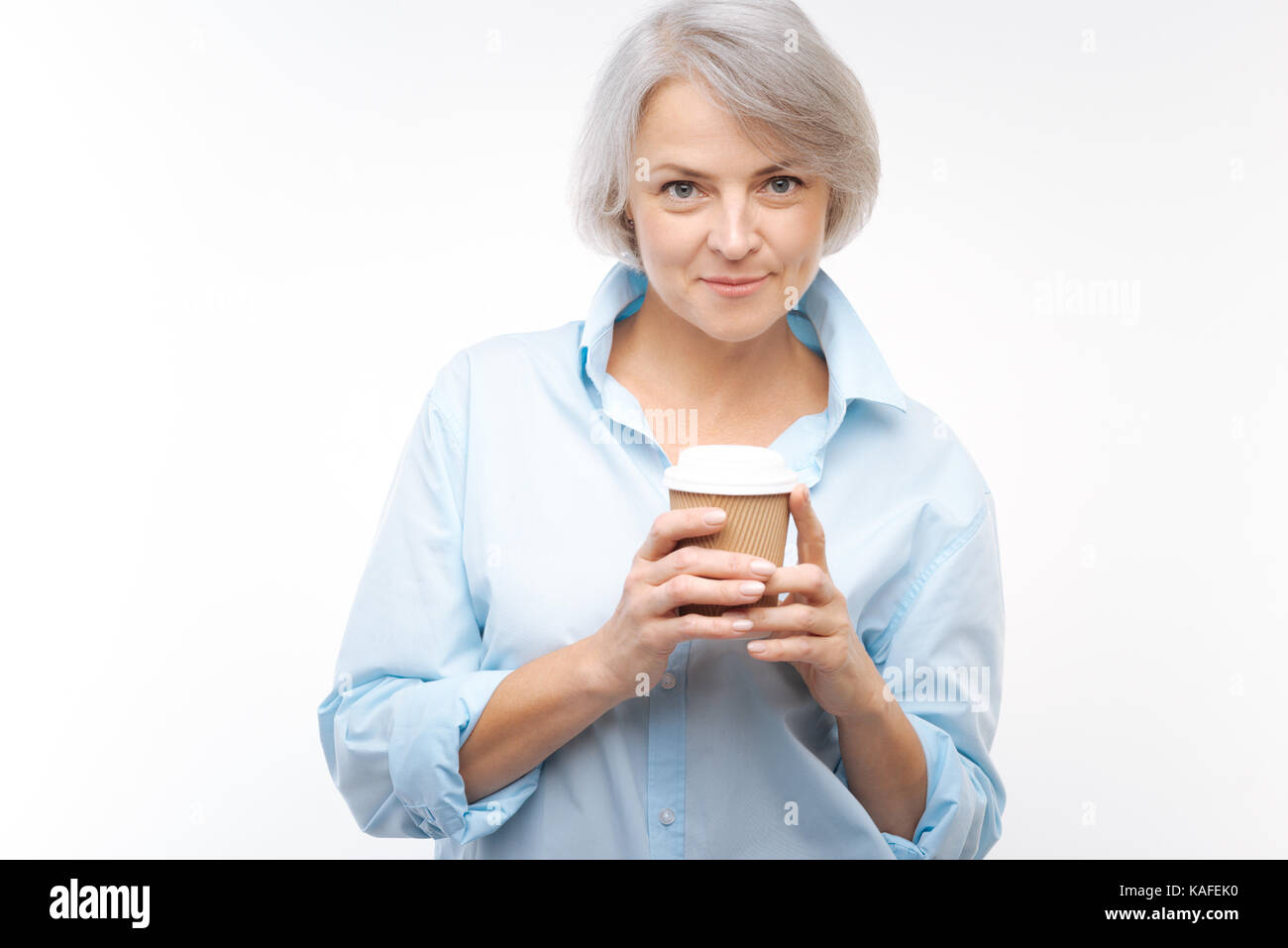 Charmante grauhaarige Frau mit Kaffee Tasse posing Stockfoto