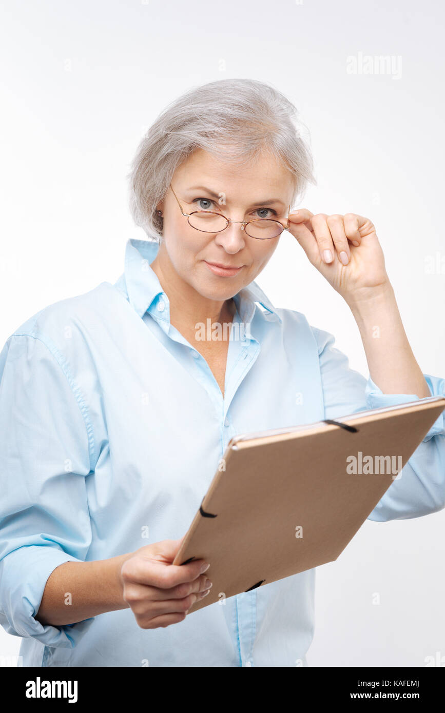 Angenehme Frau mit Ordner an Kamera suchen Stockfoto